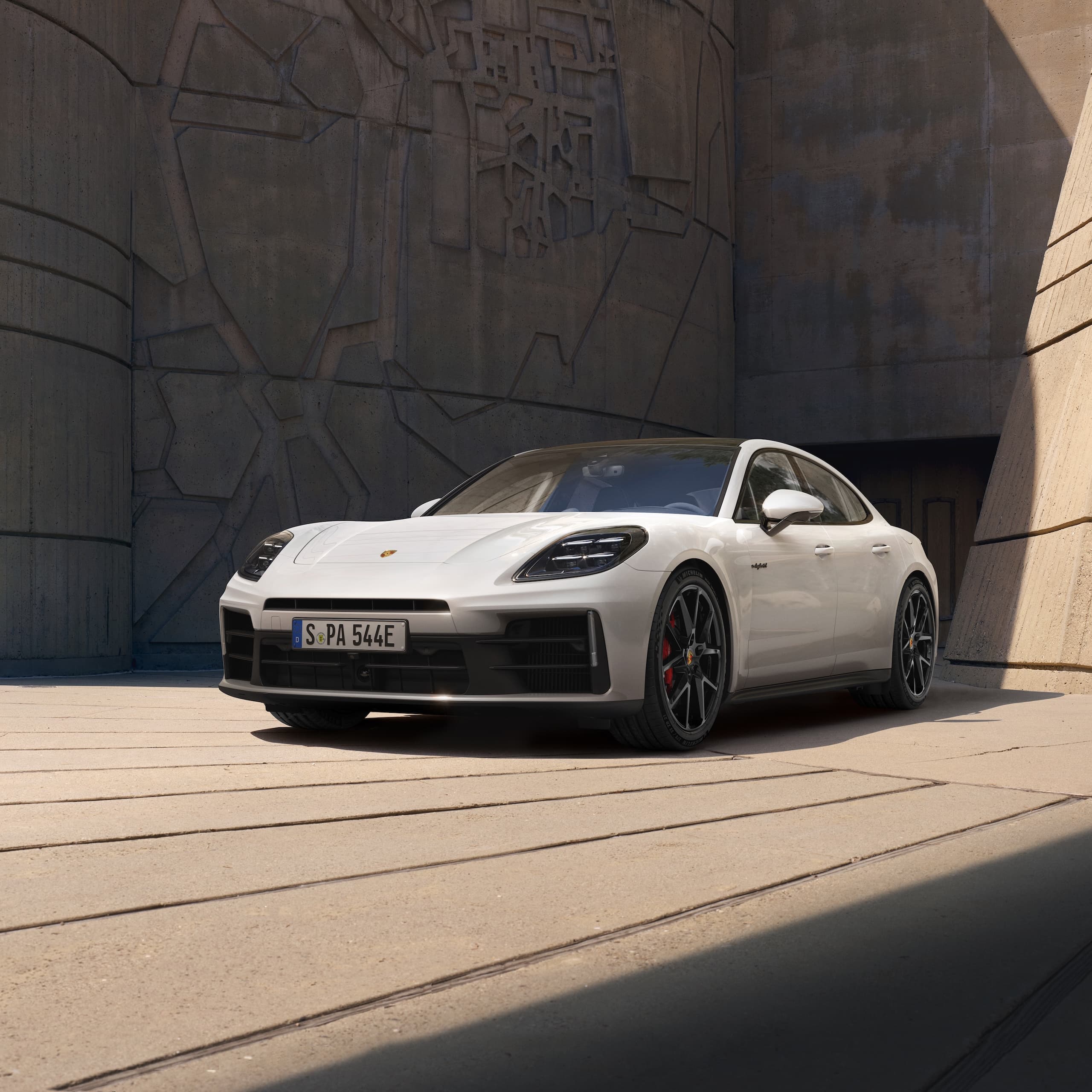 Une Porsche Panamera garée devant un immeuble moderne.